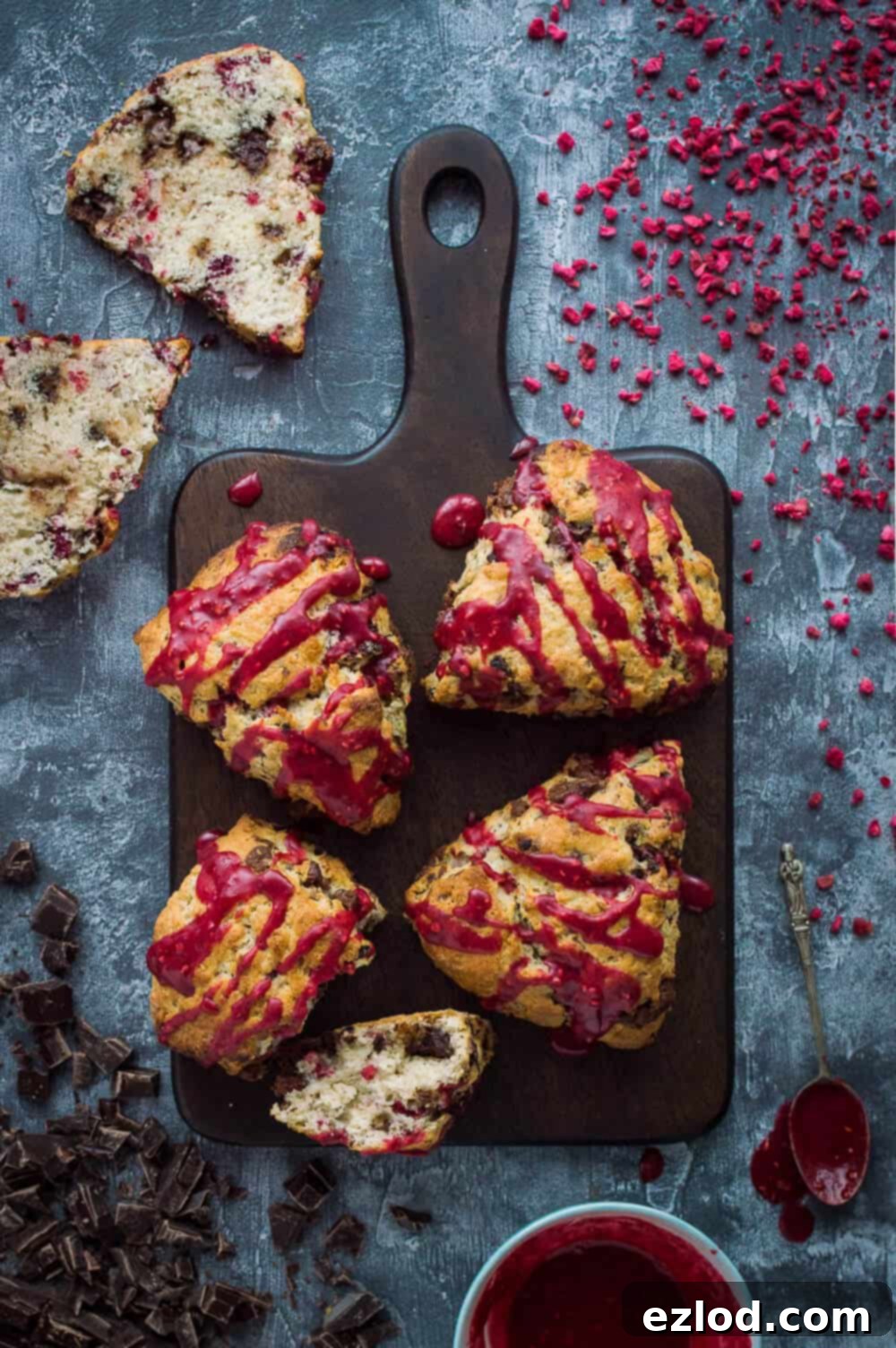 Decadent Vegan Chocolate Raspberry Scones 3 vegan chocolate raspberry scones with raspberry glaze on a wooden board.