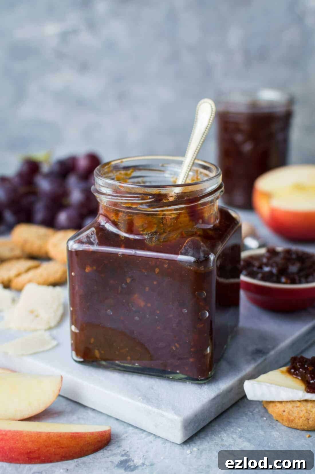 Hummus Bowl with Crispy North African Chickpeas and Fiery Caraway Jam 10 A jar of tomato, chilli and caraway jam on a marble board with cheese, crackers, grapes and apple