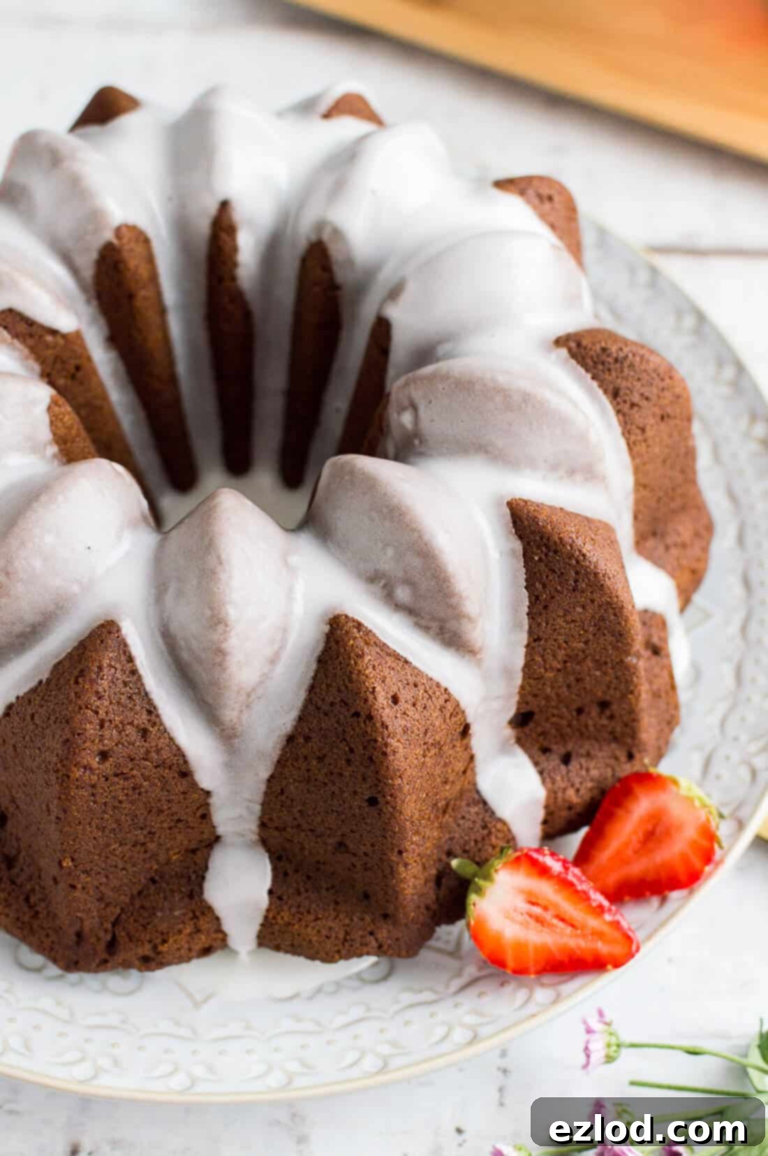 Vegan Ginger Bundt with Zesty Lime Drizzle and Sweet Strawberries 8 A close up of easy vegan gingerbread bundt cake with lime glaze and strawberries on a white plate and background.