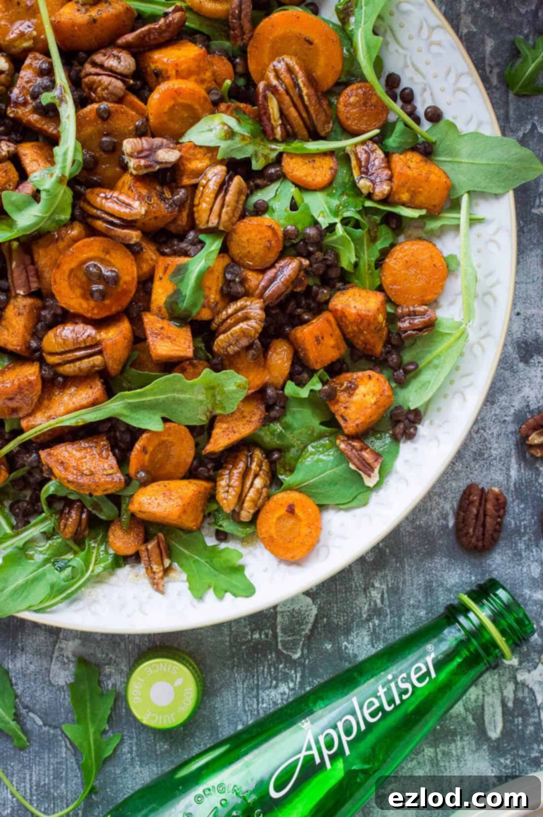 Wholesome Roasted Sweet Potato and Lentil Arugula Bowl 3 A close up of a plate of roasted sweet potato, lentil and rocket salad with a bottle of Appletiser