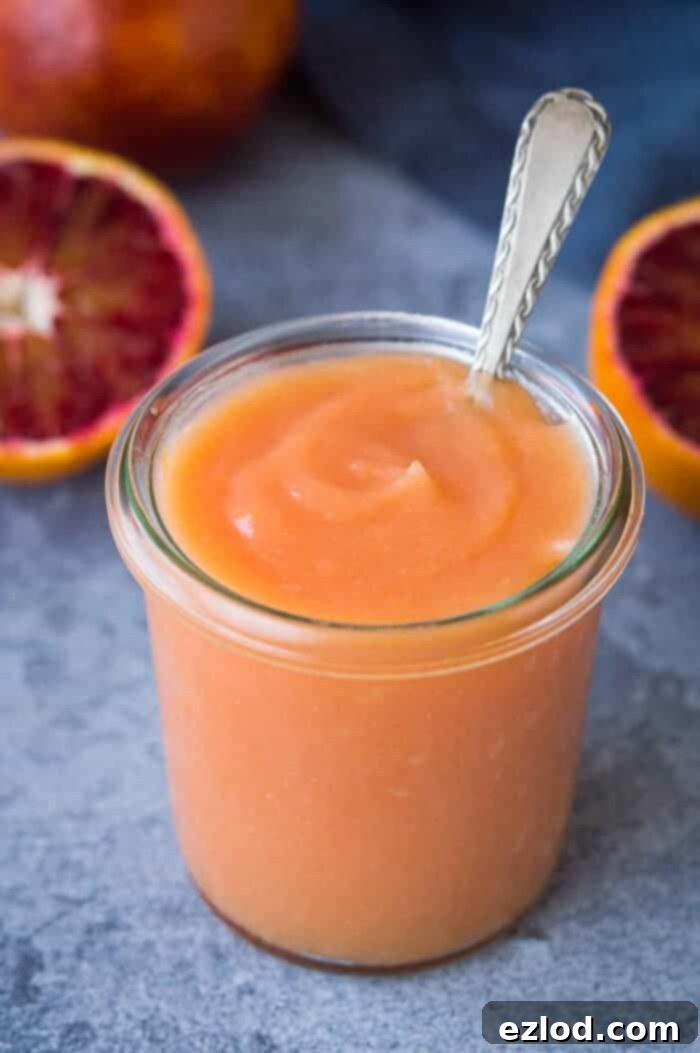 Luscious Vegan Blood Orange Curd 2 Vibrant Vegan Blood Orange Curd in a jar, showcasing its smooth texture and rich color, surrounded by fresh blood orange slices.