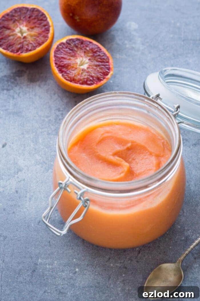 Luscious Vegan Blood Orange Curd 4 A charming glass clip-top jar brimming with homemade Vegan Blood Orange Curd, accompanied by fresh blood orange slices for garnish.