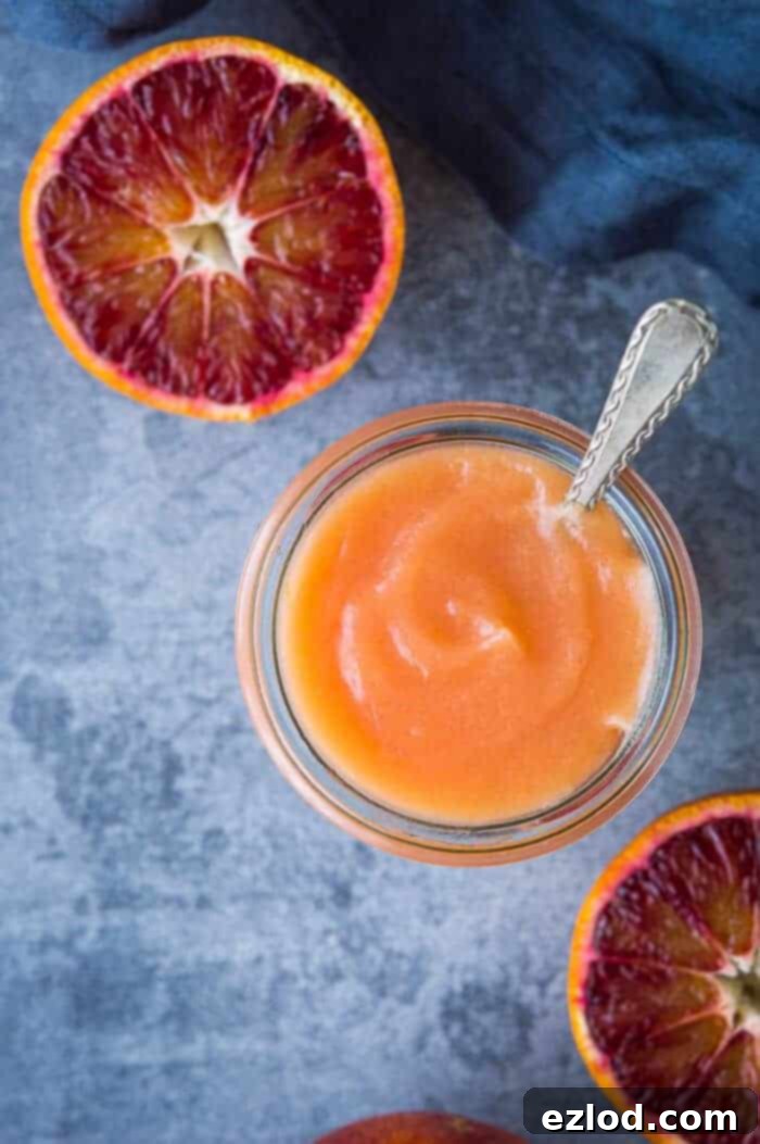 Luscious Vegan Blood Orange Curd 9 A close-up shot of a jar of homemade Vegan Blood Orange Curd, featuring a spoon dipped into the creamy texture and fresh blood orange slices artfully arranged around it.