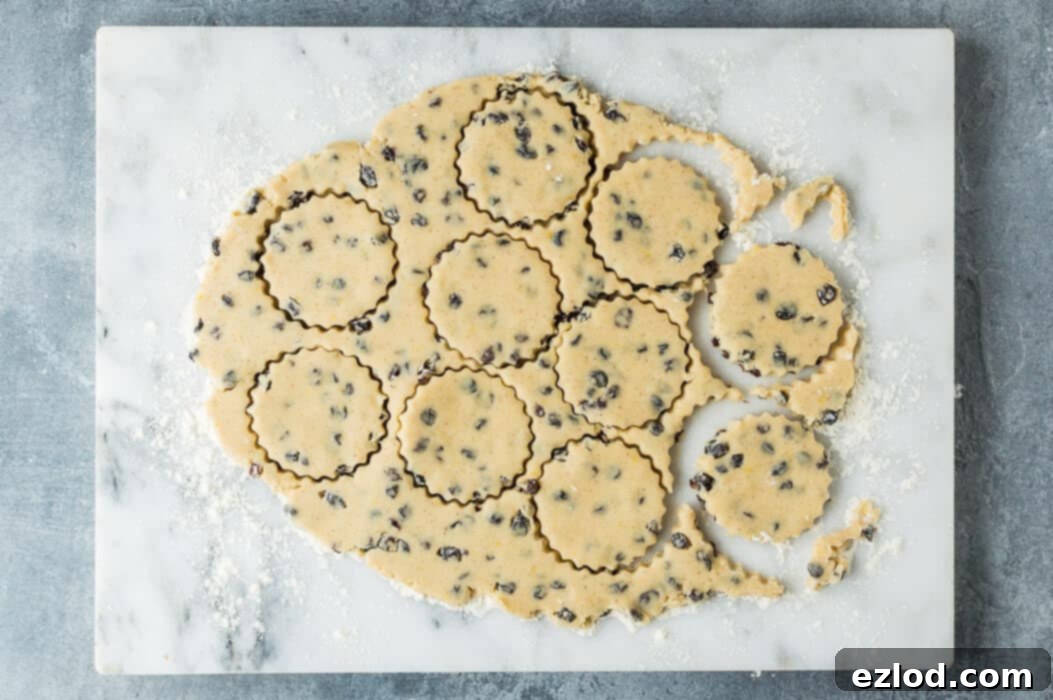 Hoppy Vegan Easter Cookies 3 step 2 - Hands rolling out vegan Easter biscuit dough on a floured surface with a rolling pin.