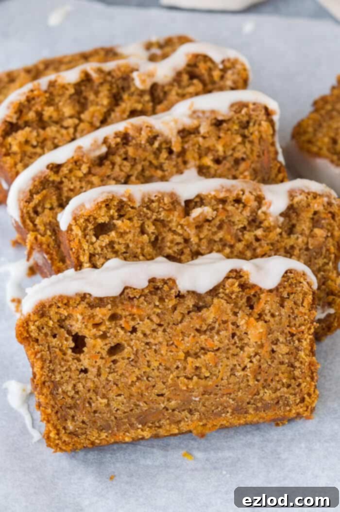 Vegan carrot cake loaf - this is the best vegan carrot cake! Easy to make, moist, sweet and spicy with a zingy lemon glaze; this loaf cake is perfect for snacking on. #vegan #carrotcake #vegancake #veganbaking Close-up view of generous slices of moist vegan carrot cake loaf, each adorned with a vibrant lemon glaze, showcasing its delightful texture and appearance.