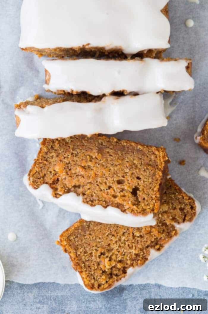 Vegan carrot cake loaf - this is the best vegan carrot cake! Easy to make, moist, sweet and spicy with a zingy lemon glaze; this loaf cake is perfect for snacking on. #vegan #veganbaking #vegancake #vegancarrotcake #loafcake #snackcake #carrotcake #eggless #dairyfree #eggfree Close-up of perfectly sliced vegan carrot cake loaf, showcasing its moist crumb and topped with a luscious lemon glaze, ready to be enjoyed.