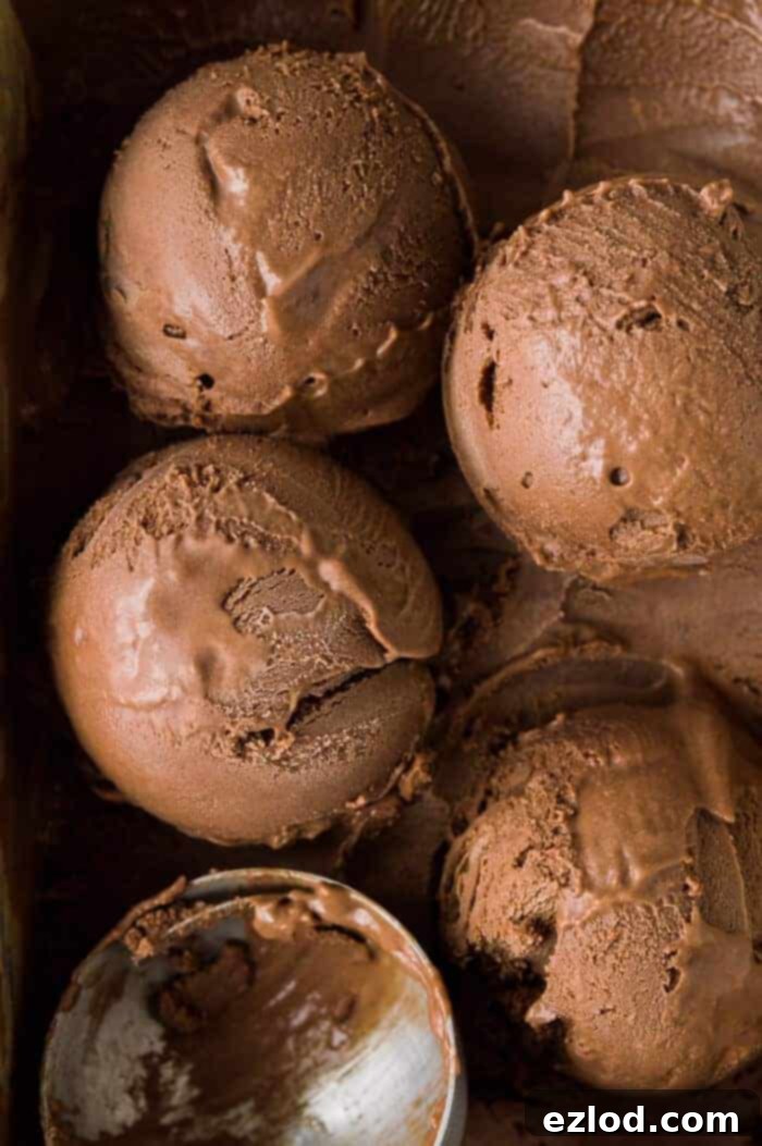 Rich and creamy vegan chocolate ice cream - this is the creamiest vegan chocolate ice cream with no hint of iciness and a rich chocolate flavour. Made with cashews and coconut milk for the smoothest, most decadent texture. NO bananas! #vegan #plantbased #veganicecream #chocolateicecream #dairyfree #eggless #icecream Close up of scoops of creamy vegan chocolate ice cream.