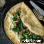 Plant-Powered Crepes: Spinach, Mushroom & Creamy Almond Cheese 4 Close up of a vegan mushroom, spinach and cheese pancake on a black plate.
