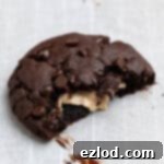 Close up of a vegan peanut butter stuffed chocolate cookie with a piece broken off.