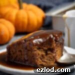 Spiced Pumpkin Sticky Toffee Pudding 15 A square of vegan pumpkin sticky toffee pudding on a plate with a spoonful removed.