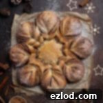 Vegan Cinnamon Star Bread 21 Vegan cinnamon star bread on a dark surface surrounded by cinnamon sticks, pine cones and Christmas decorations.