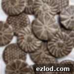 A pile of vegan glazed gingerbread cookies on a sheet of baking paper.