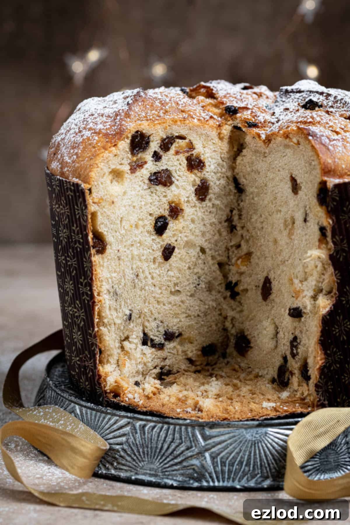 Close up of the sliced vegan panettone on a metal plate with a gold ribbon.
