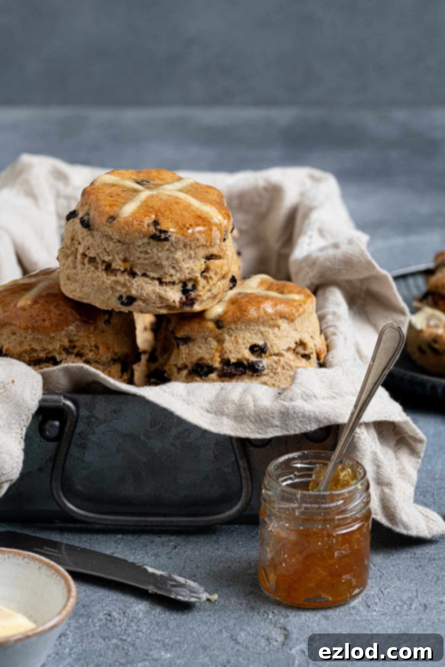 Hot cross scones in a metal box with marmalade and butter.
