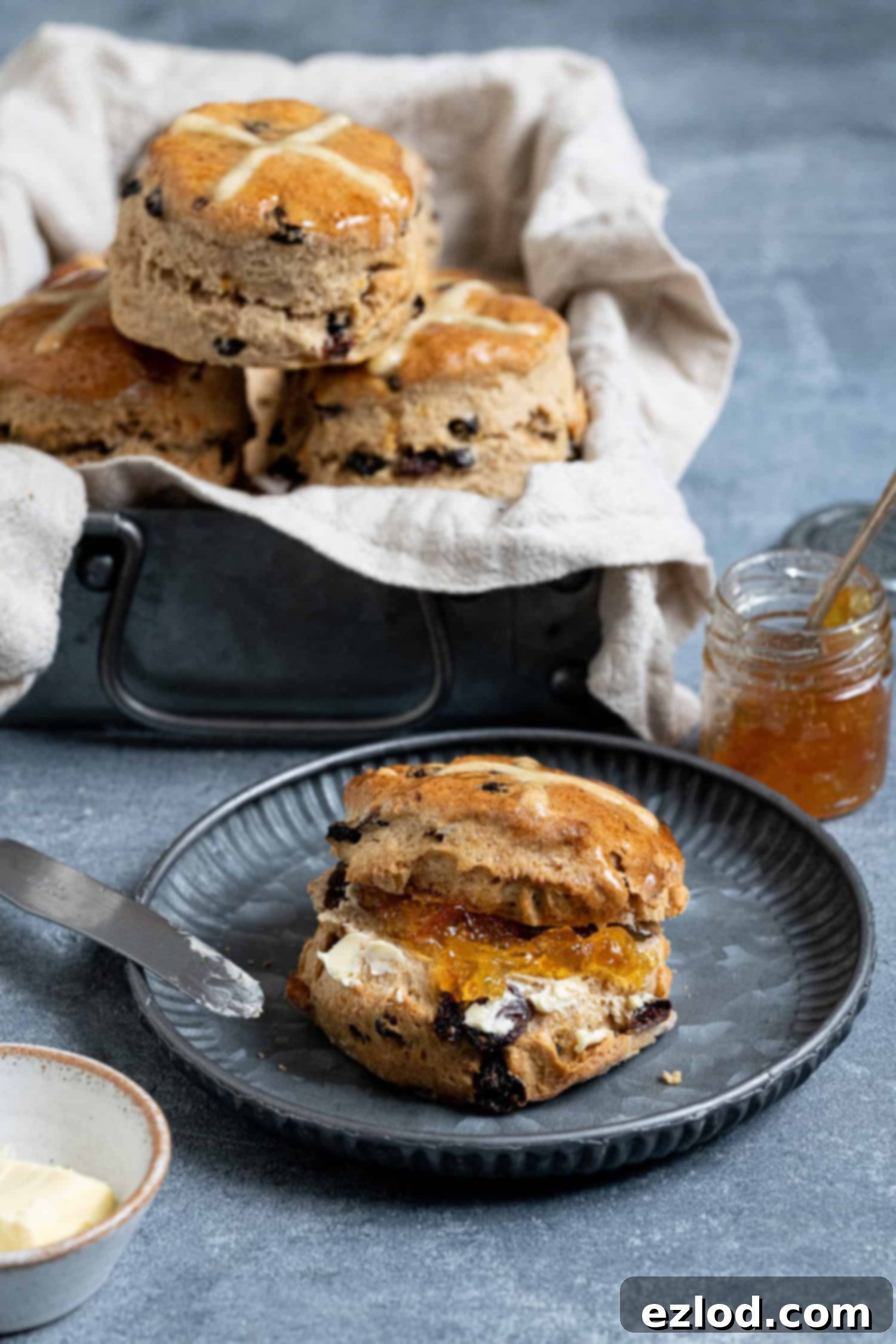 A scone sliced in half and filled with butter and marmalade.
