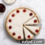 The sliced vegan Manchester tart on a marble board with bowls of coconut and glace cherries.